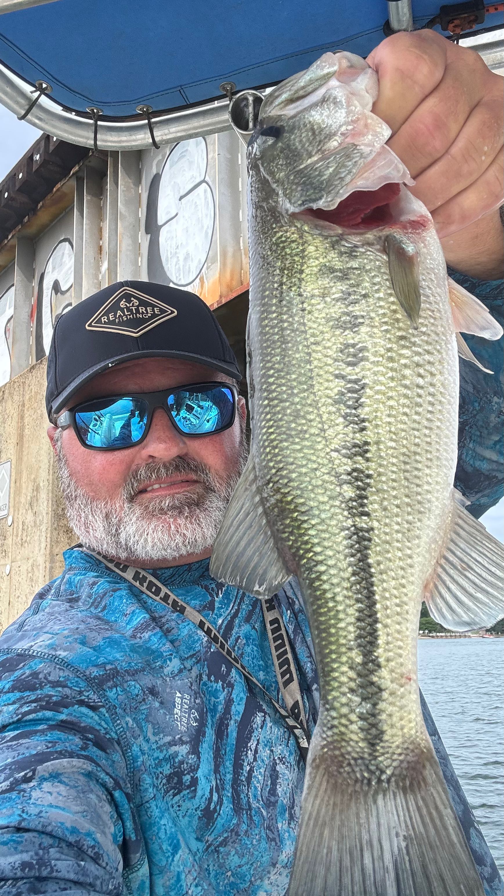 Large bass fish being held up on fishing boat in Denver NC