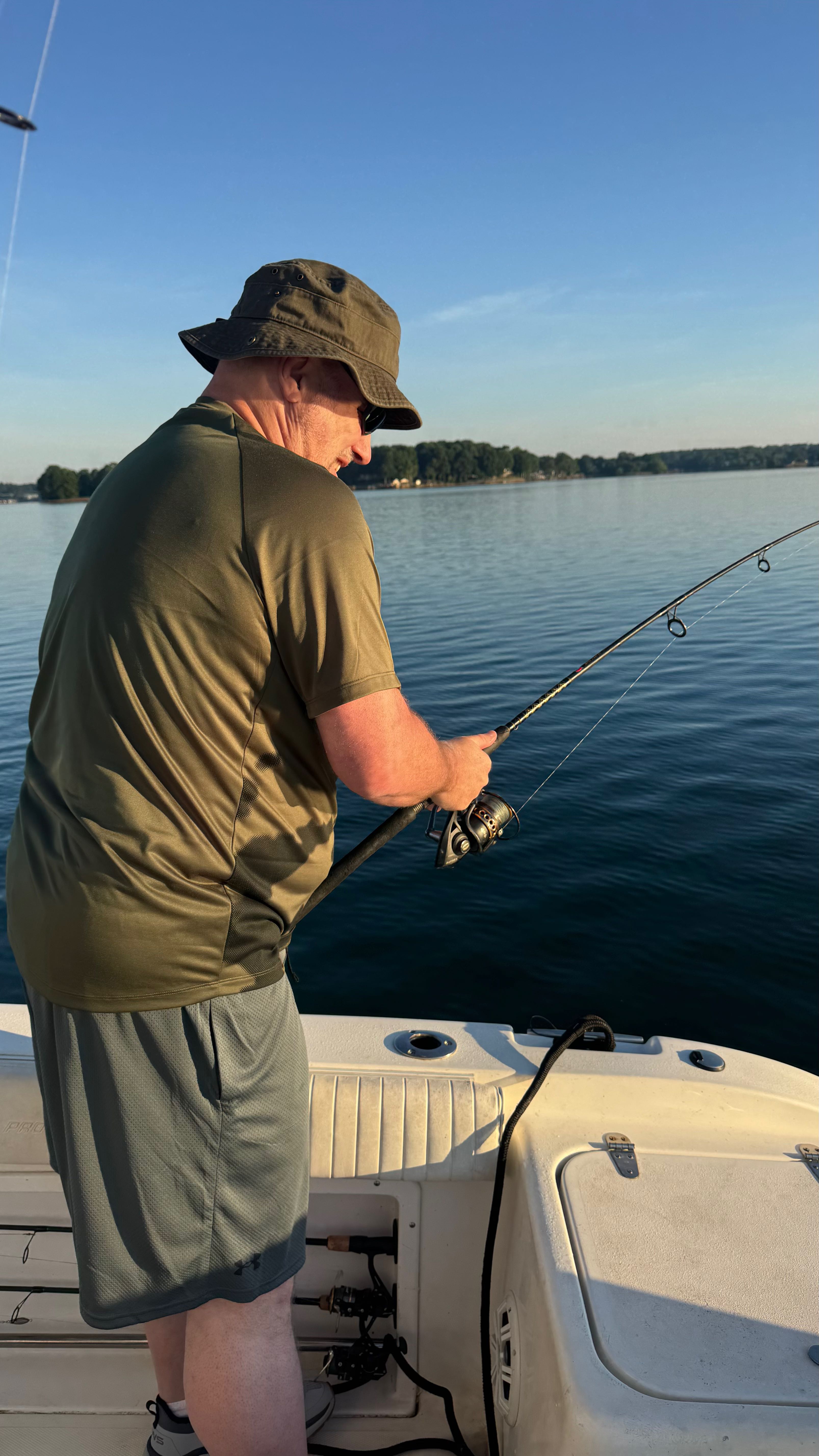 Fishing rod cast over calm lake water near Denver NC with wooded shoreline in background