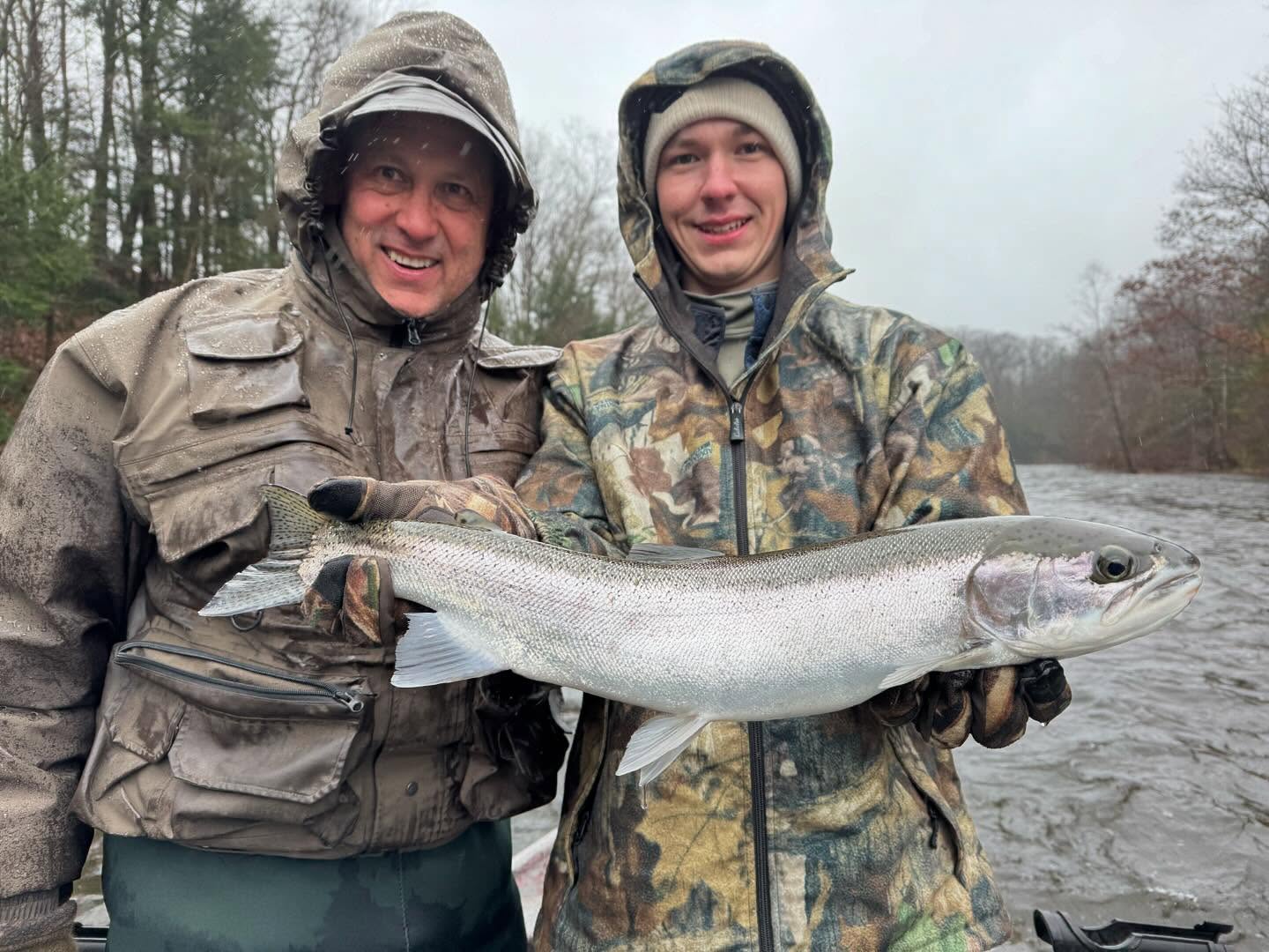 Two anglers holding a large salmon catch on a river in Mexico NY during a successful fishing trip