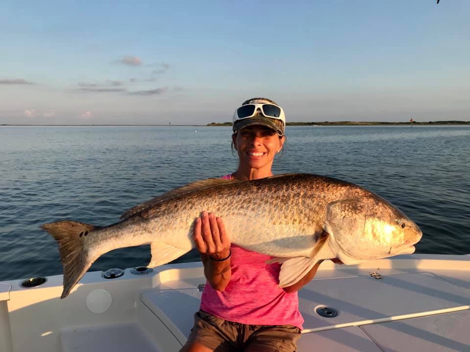 Photograph of a fisherman holding a large redfish in LA