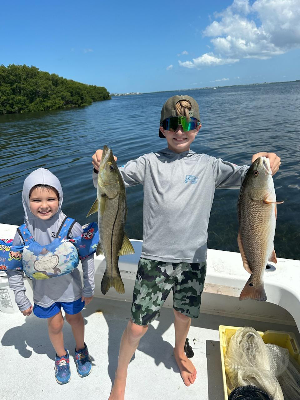 Kids learning to fish in shallow Florida waters near Cortez mangroves on family charter boat