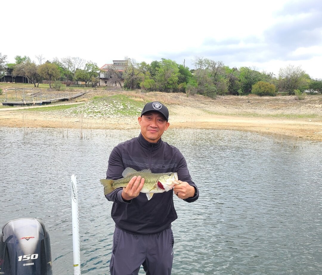 Angler holding freshly caught bass on lake in Austin TX