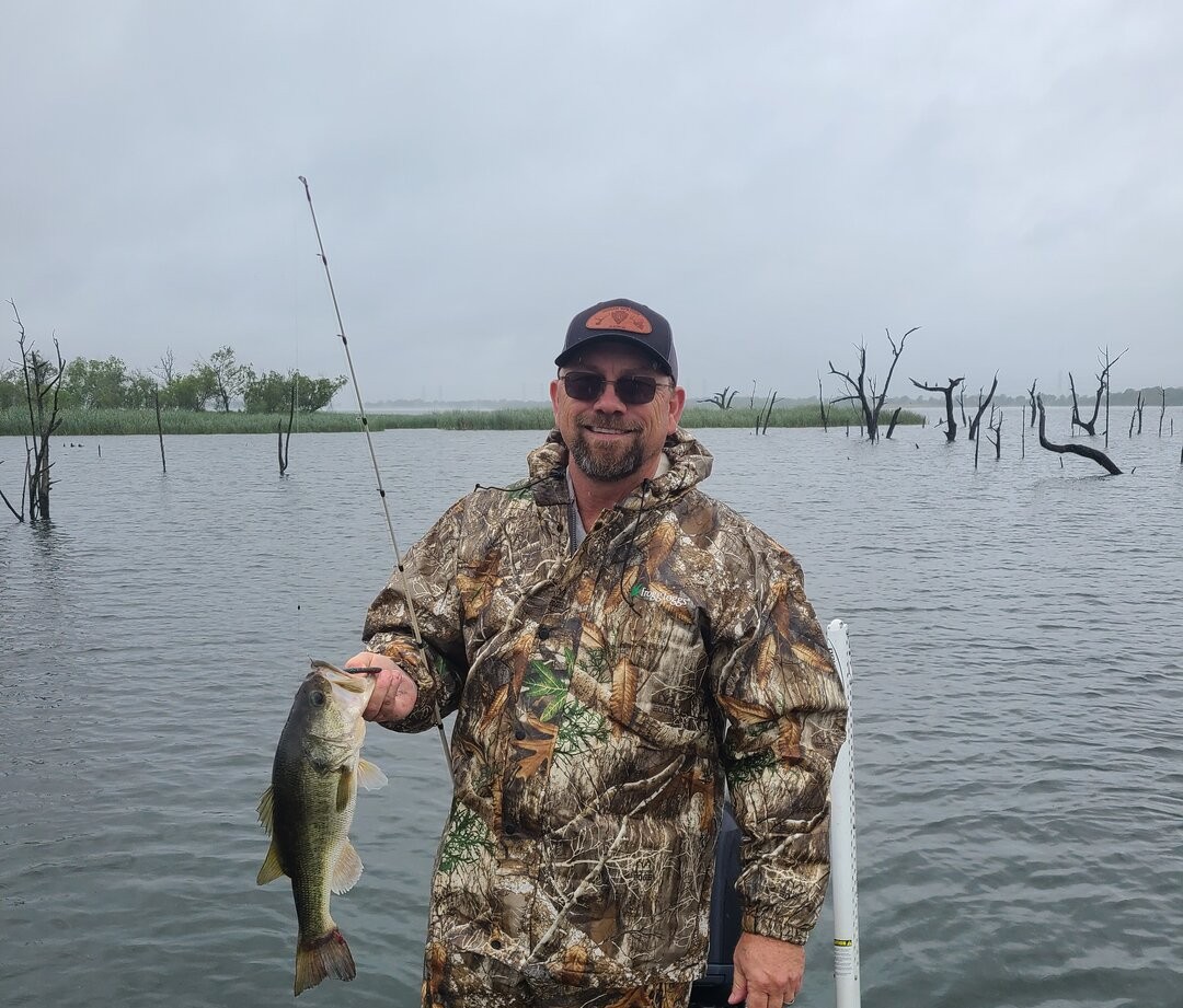 Bass fishing catch displayed on boat in Austin TX lake with dead trees in background