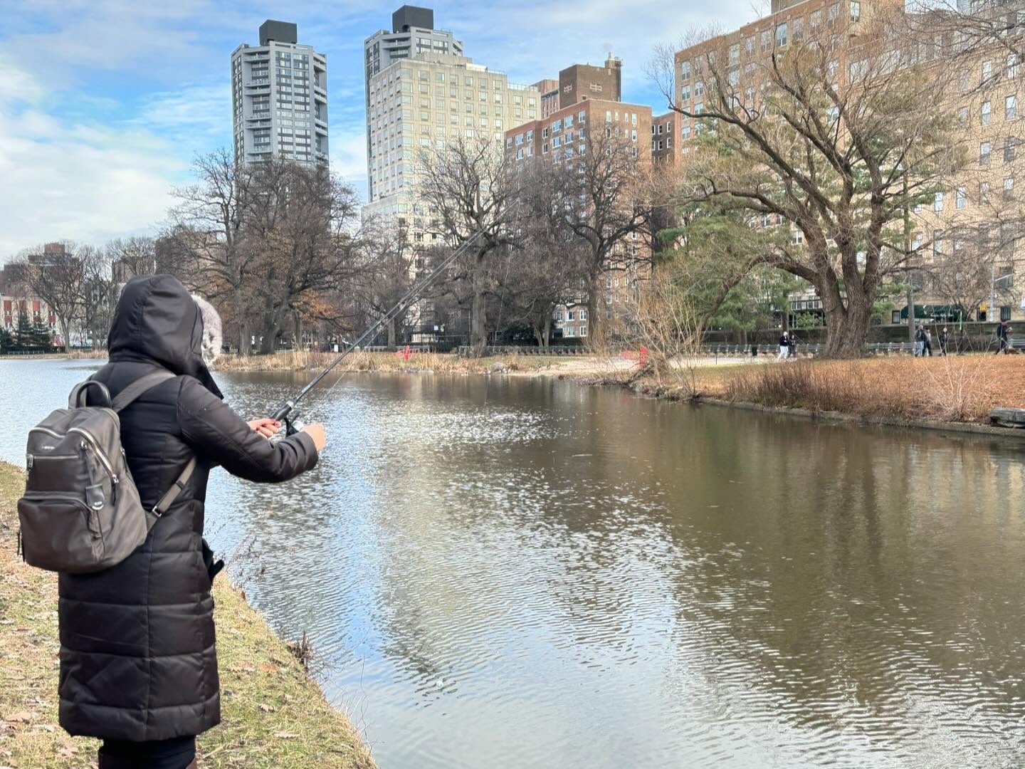 Smallmouth bass fishing guide with rod at Harlem Meer lake in Central Park, New York City