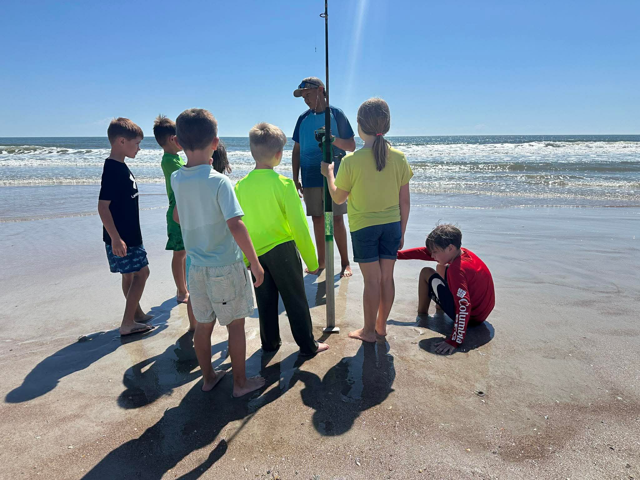 Group learning beach fishing techniques with fishing rod on Fernandina Beach FL shore