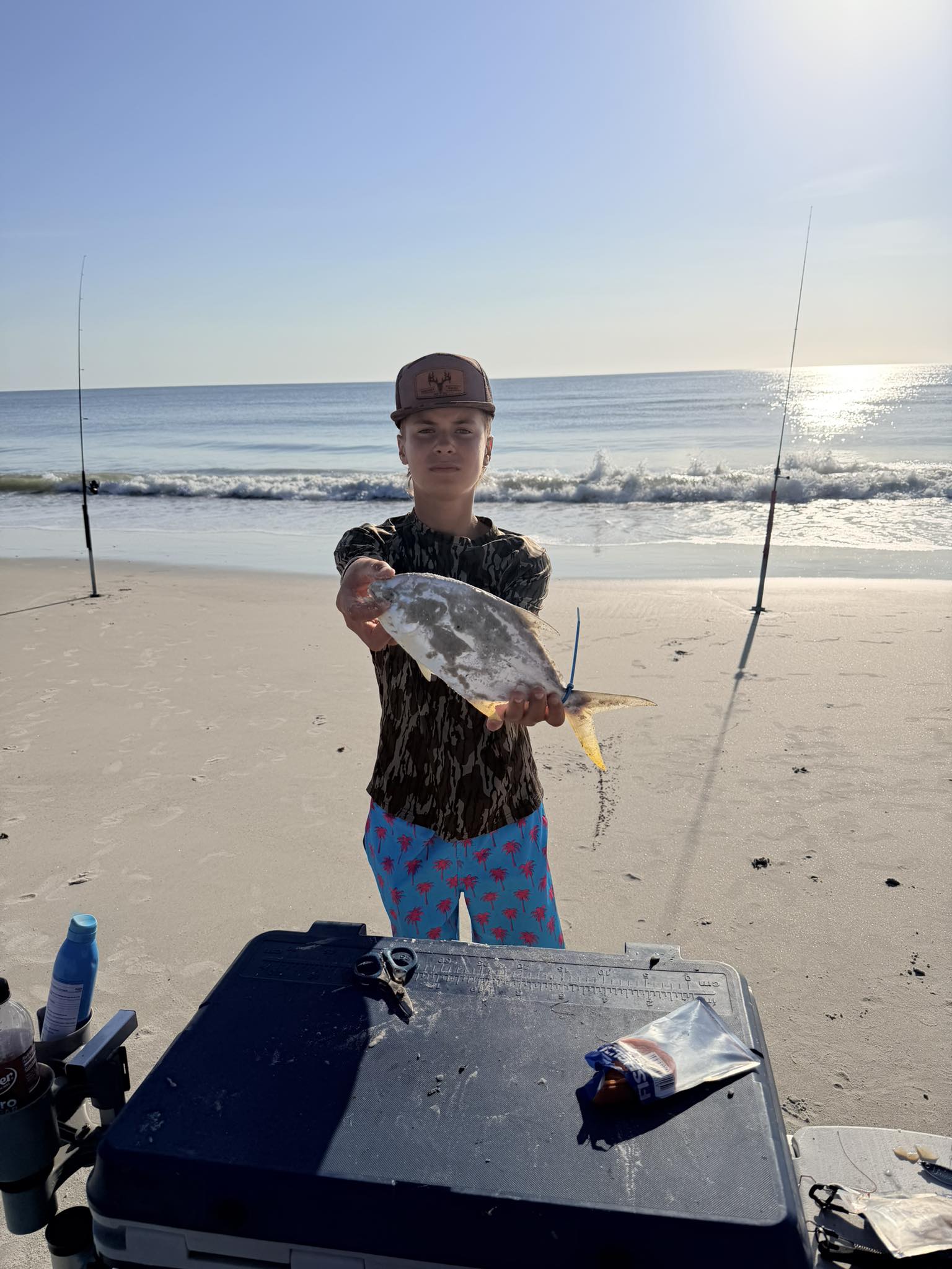 Angler holding caught fish on beach at Fernandina Beach FL with fishing rods in background