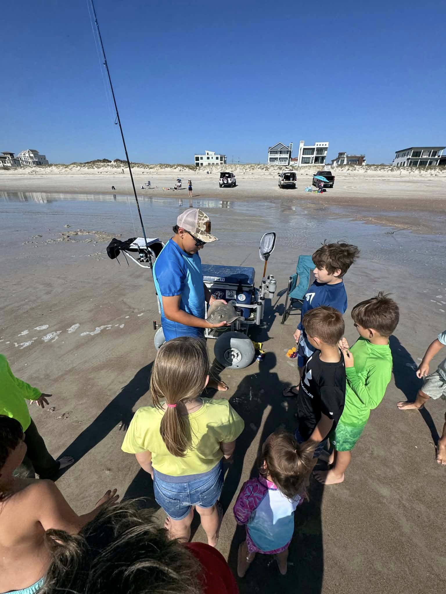 Children gathered around fishing equipment on Fernandina Beach FL during educational fishing demonstration
