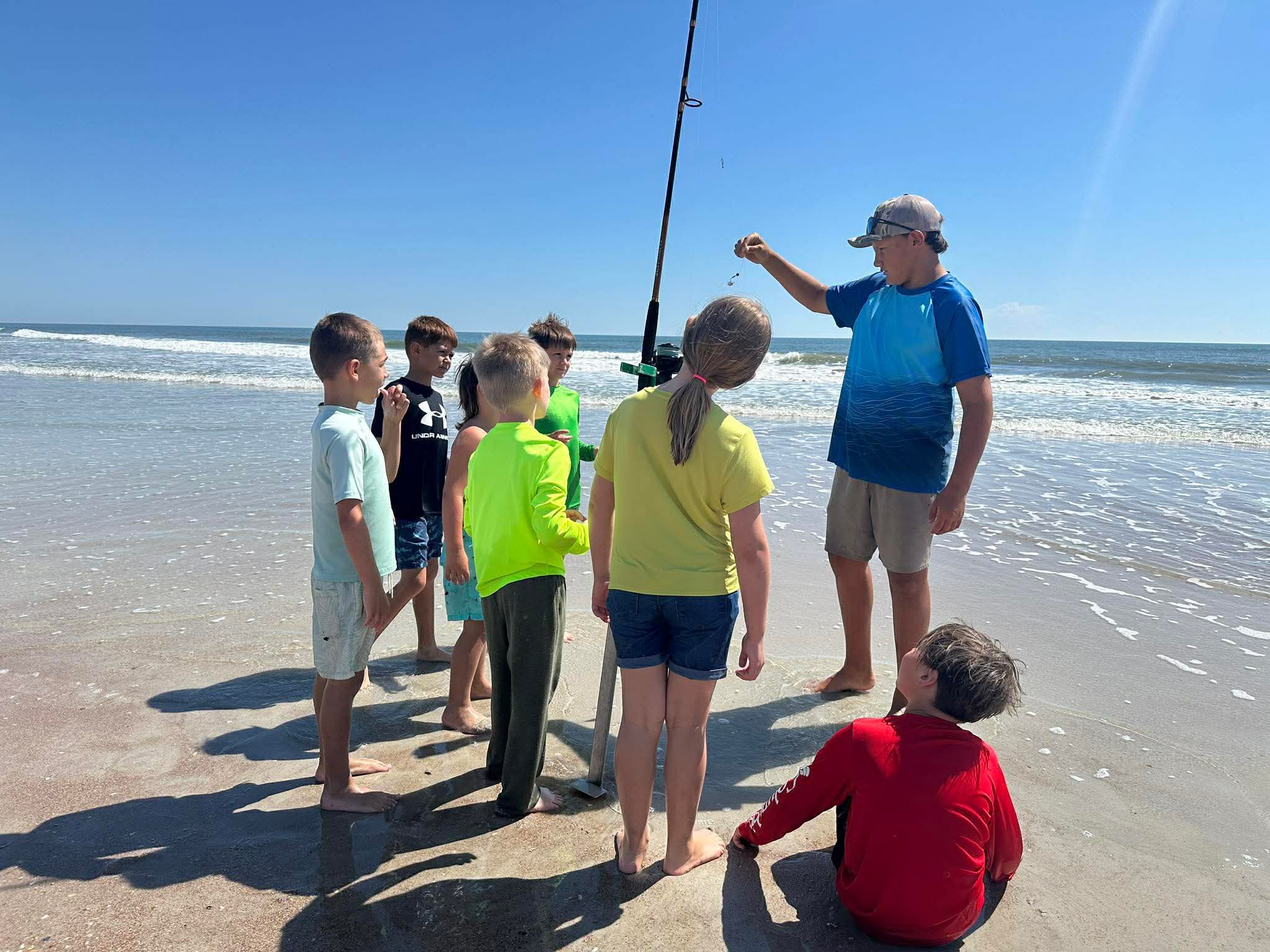 Fishing lesson on Fernandina Beach FL with instructor teaching children surf fishing techniques