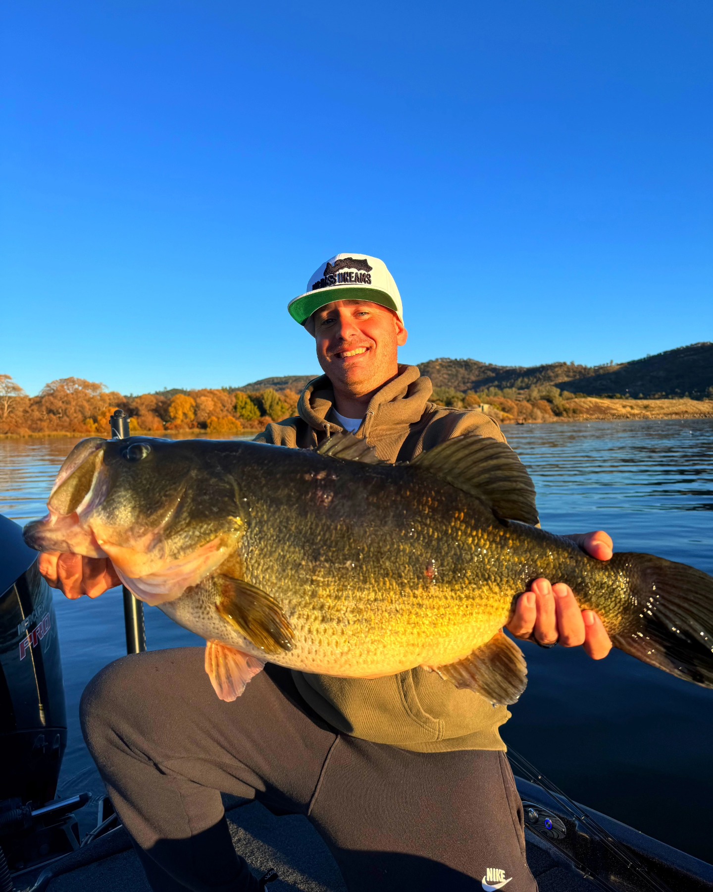Angler holding large bass fish on boat in Collinsville TX lake during golden hour