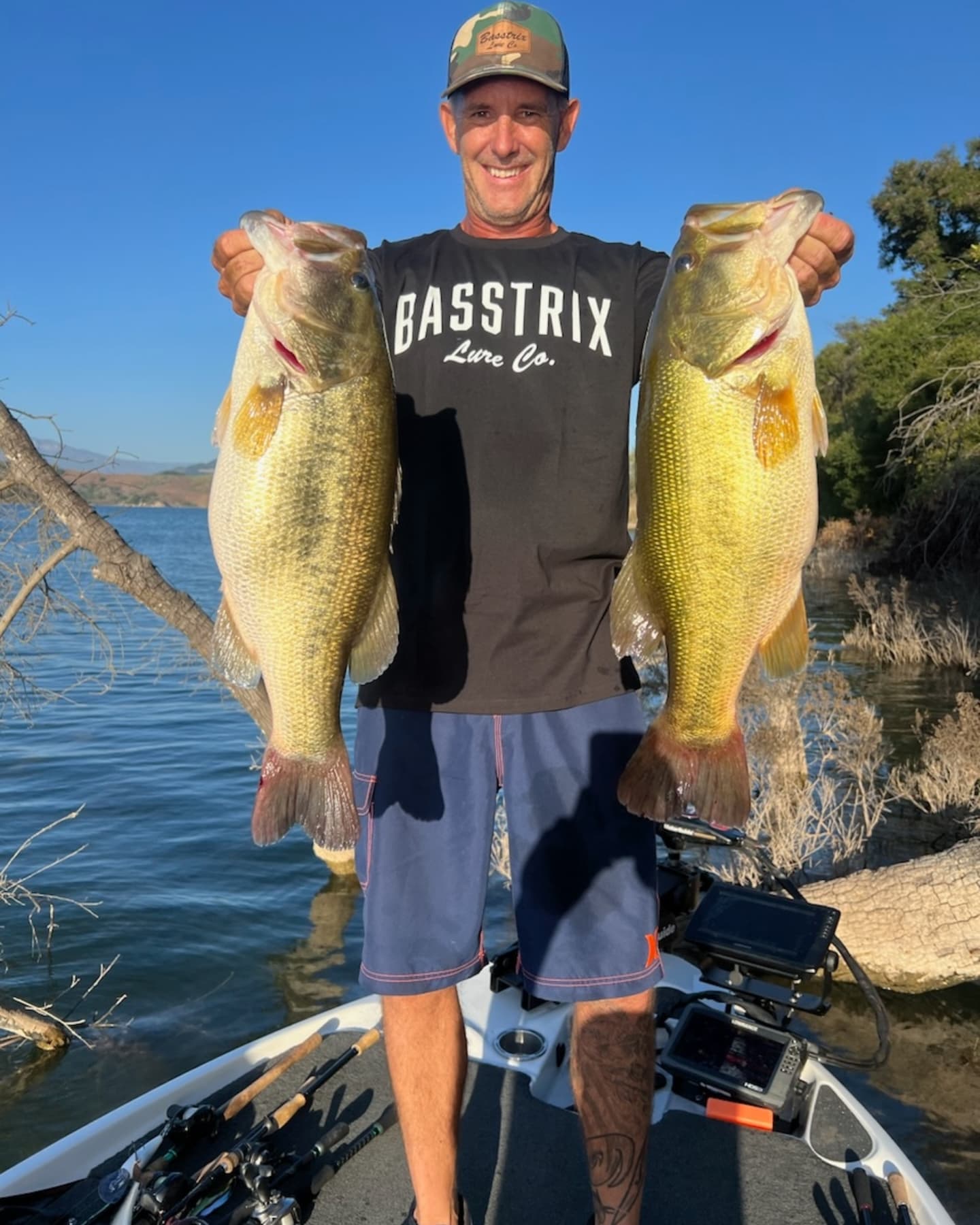 Angler holding two large bass fish on boat at lake in Collinsville TX