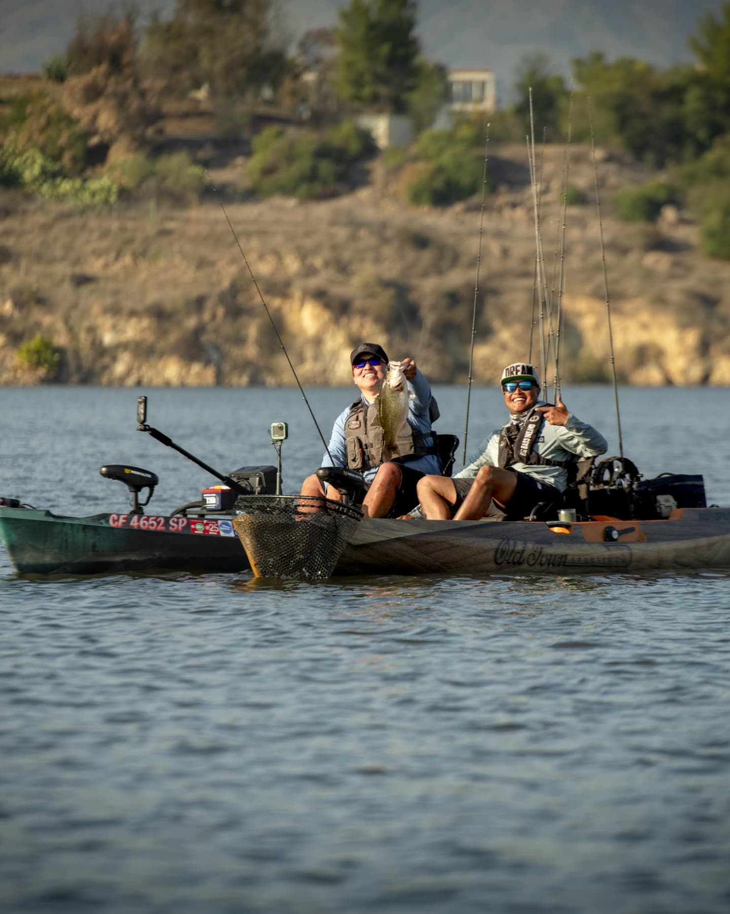 Two anglers fishing from kayak on lake in Collinsville TX holding caught fish