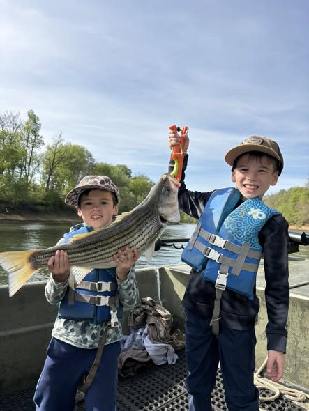 Two young anglers holding a striped bass catch while fishing in Weldon NC