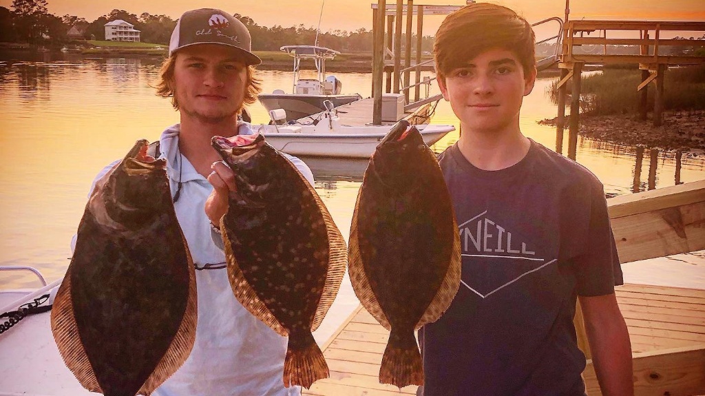2 anglers holding 3 summer flounder fish caught in NC