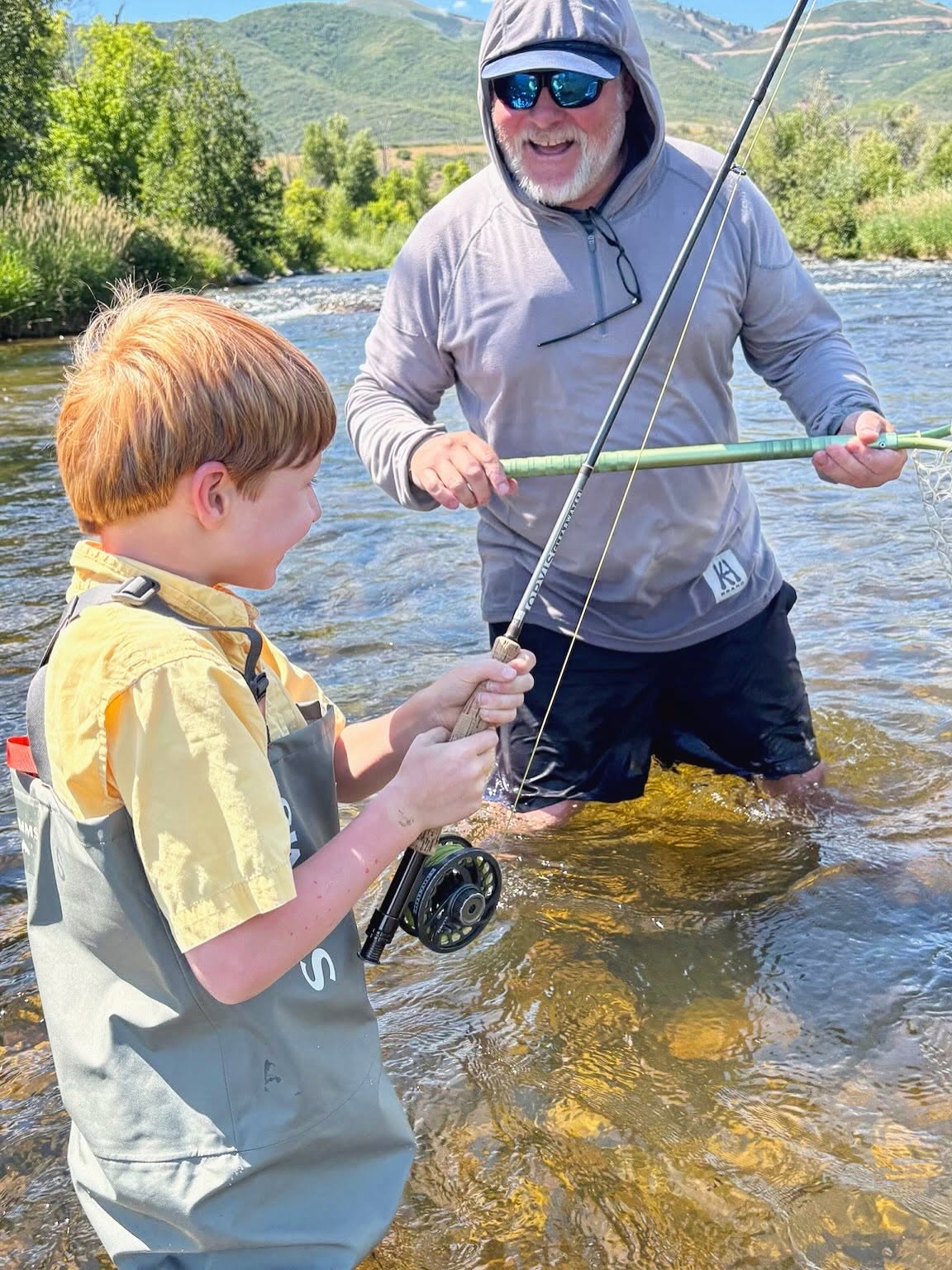 Fly fishing instruction on river in Park City UT with mountains in background