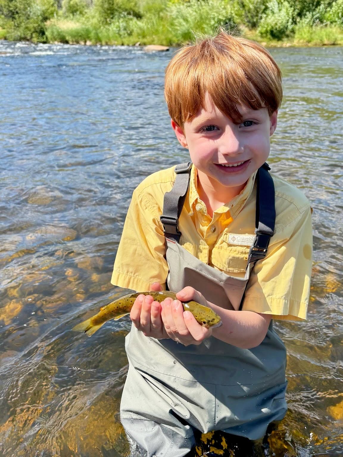 Small fish held in cupped hands while standing in flowing river in Park City UT