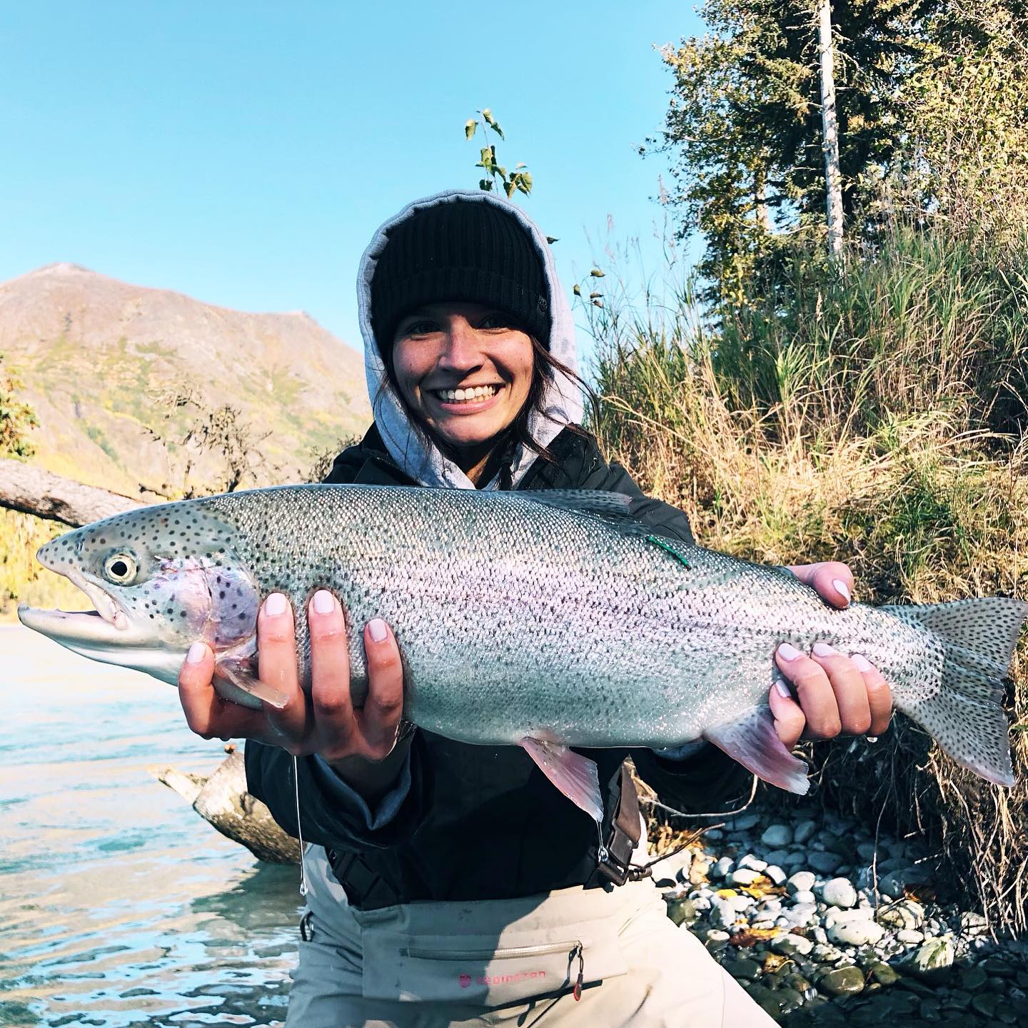 Proud angler with a rainbow trout catch in Alaska