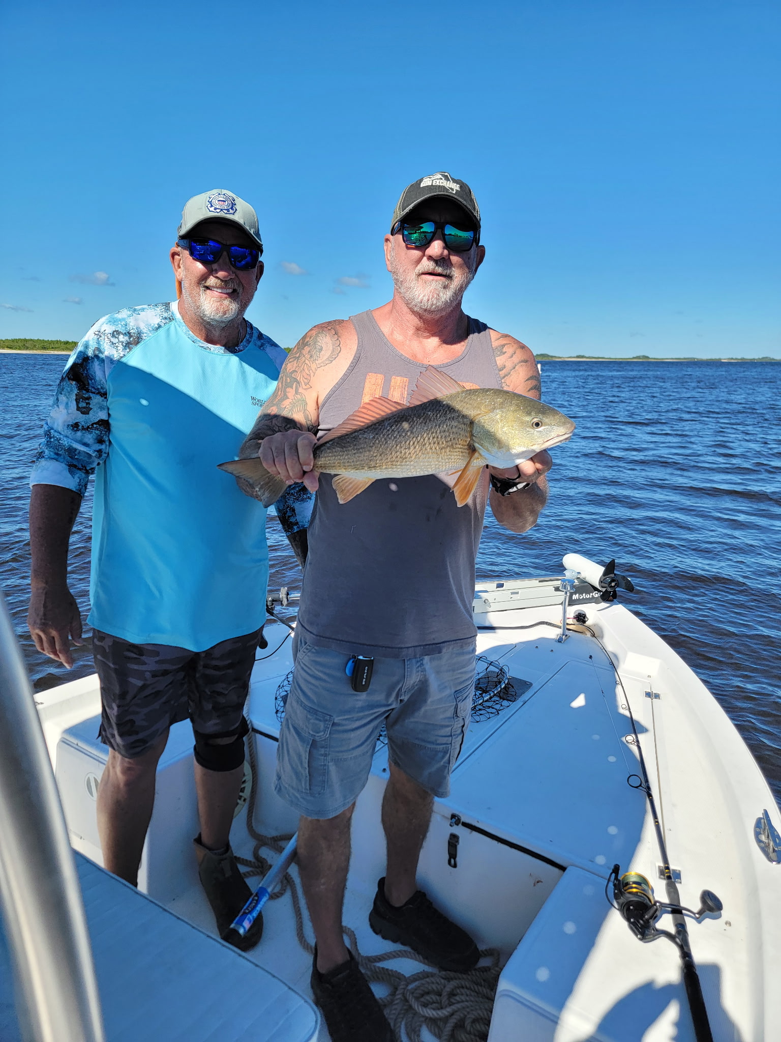Two anglers displaying a caught redfish on fishing boat in Ponce Inlet FL waters