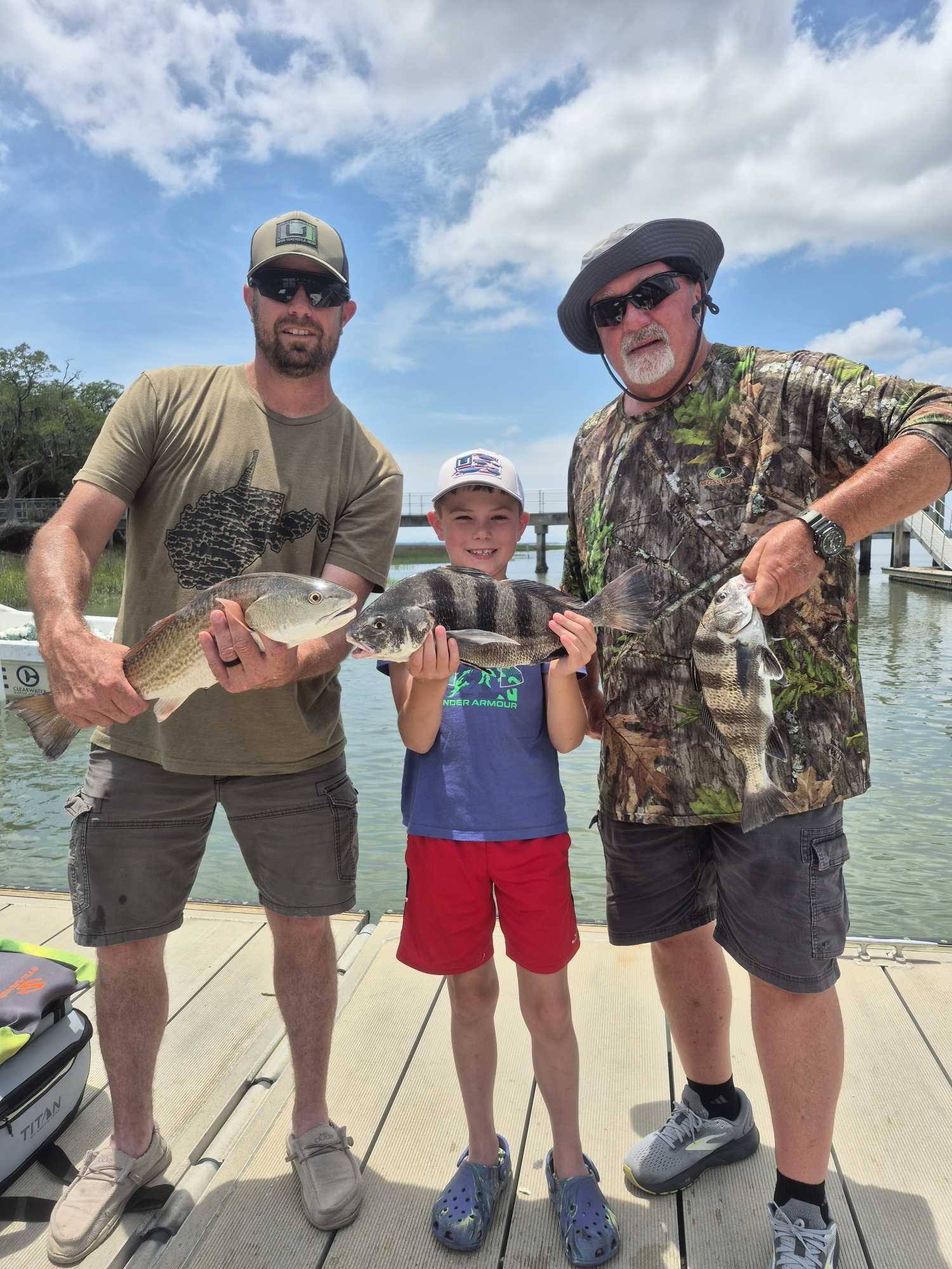 Three anglers displaying their catch of redfish and black drum on a dock at Hilton Head Island SC