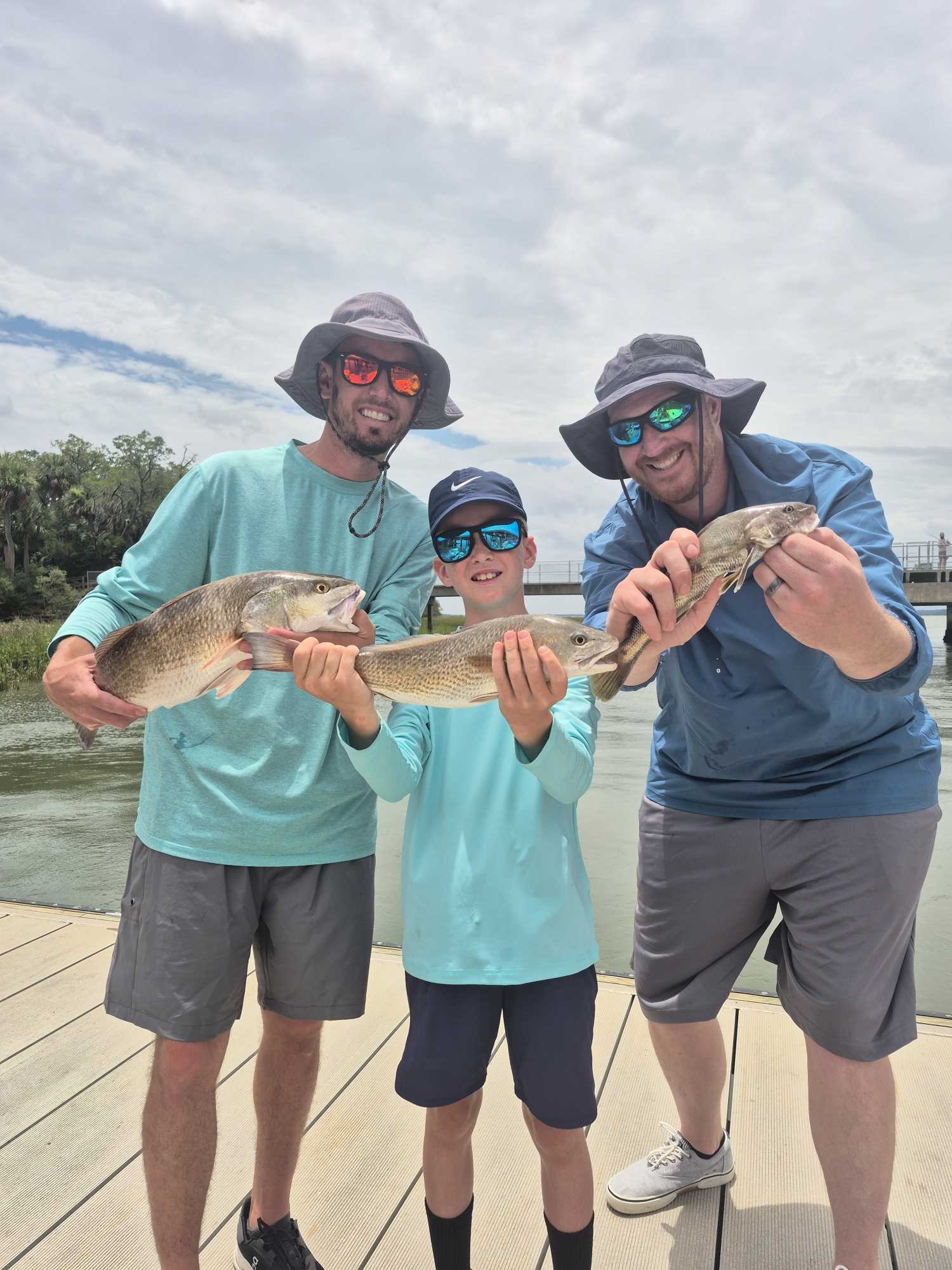 Three anglers displaying their redfish catch on a dock at Hilton Head Island SC