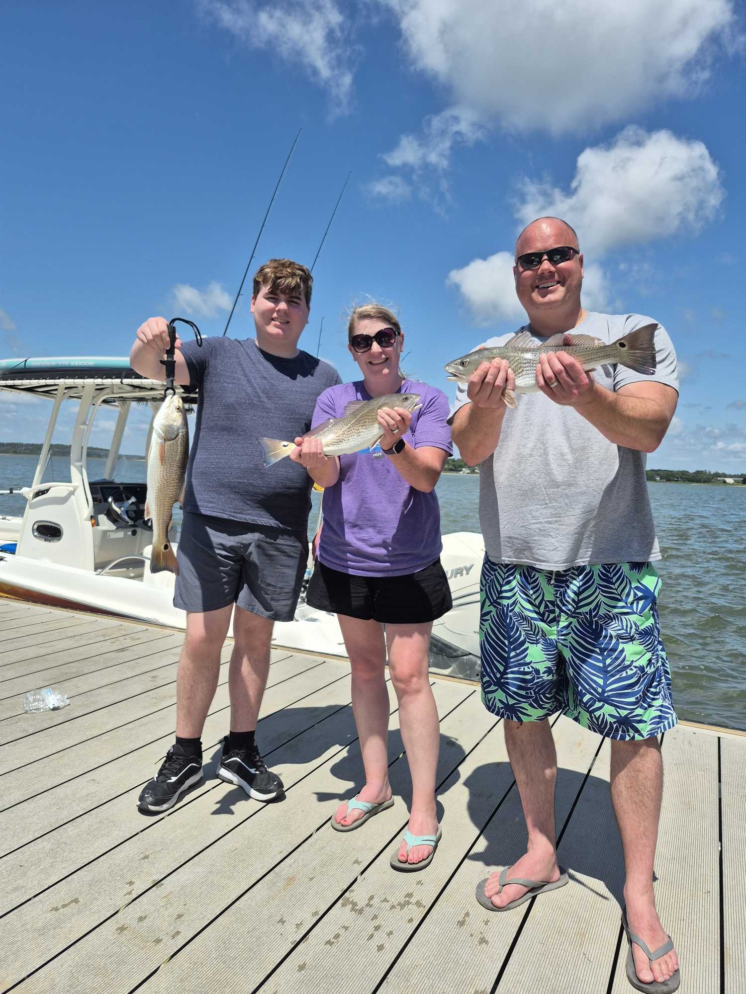 Three anglers displaying caught redfish on fishing dock at Hilton Head Island SC