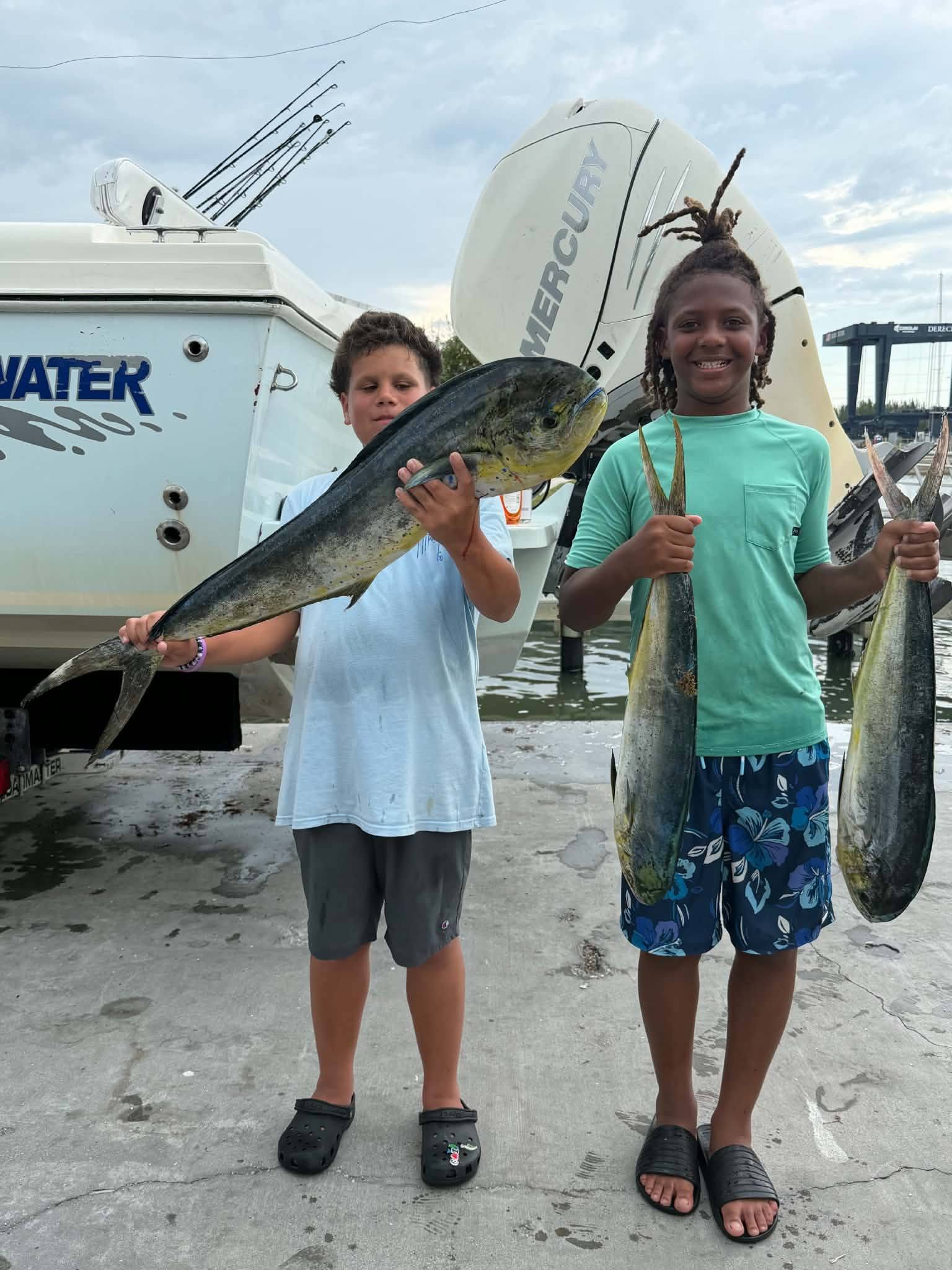Two young anglers display freshly caught mahi mahi fish at Fort Pierce FL marina