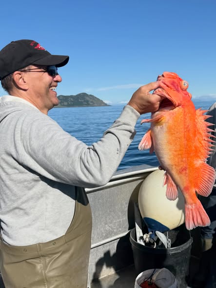 Angler holding large orange rockfish on fishing boat in Larsen Bay Alaska