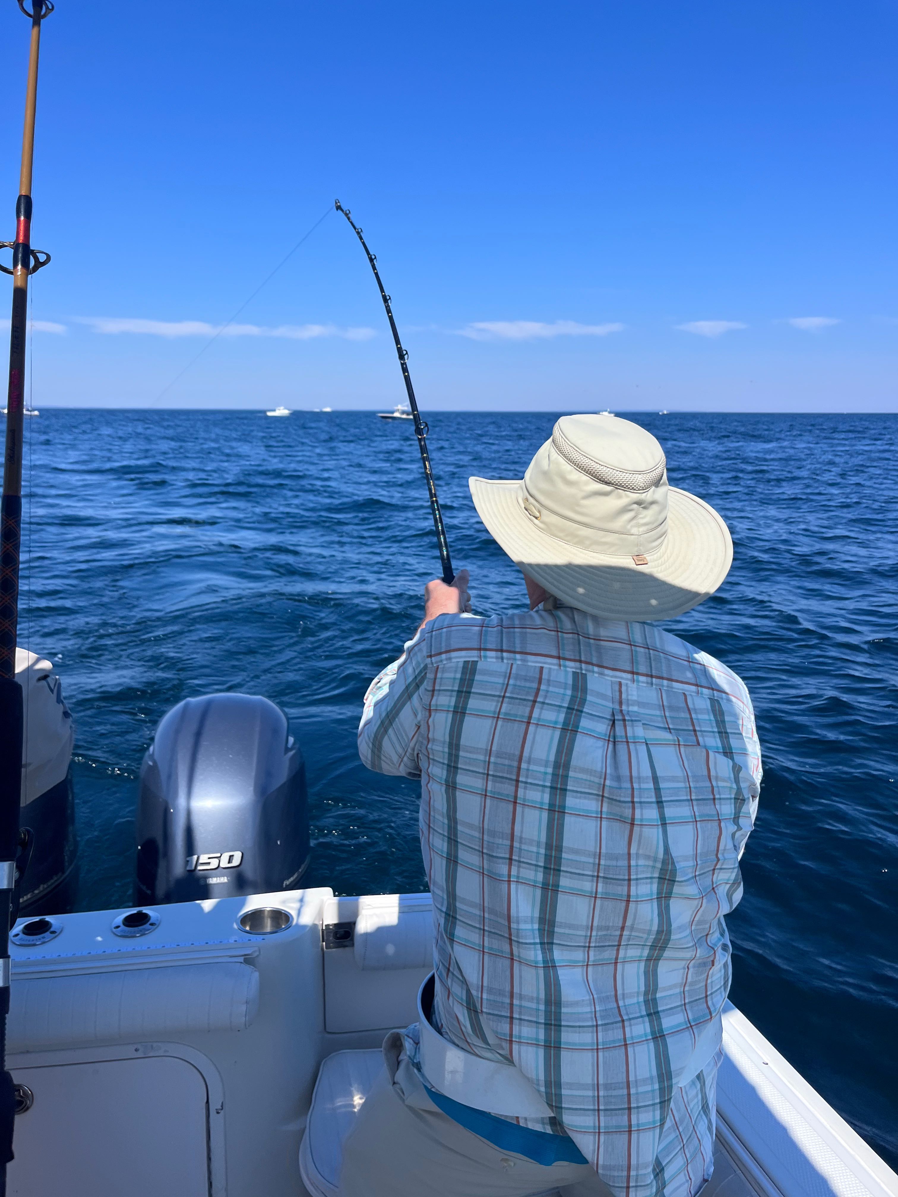 Fishing rod held over blue ocean water from boat in East Dennis MA