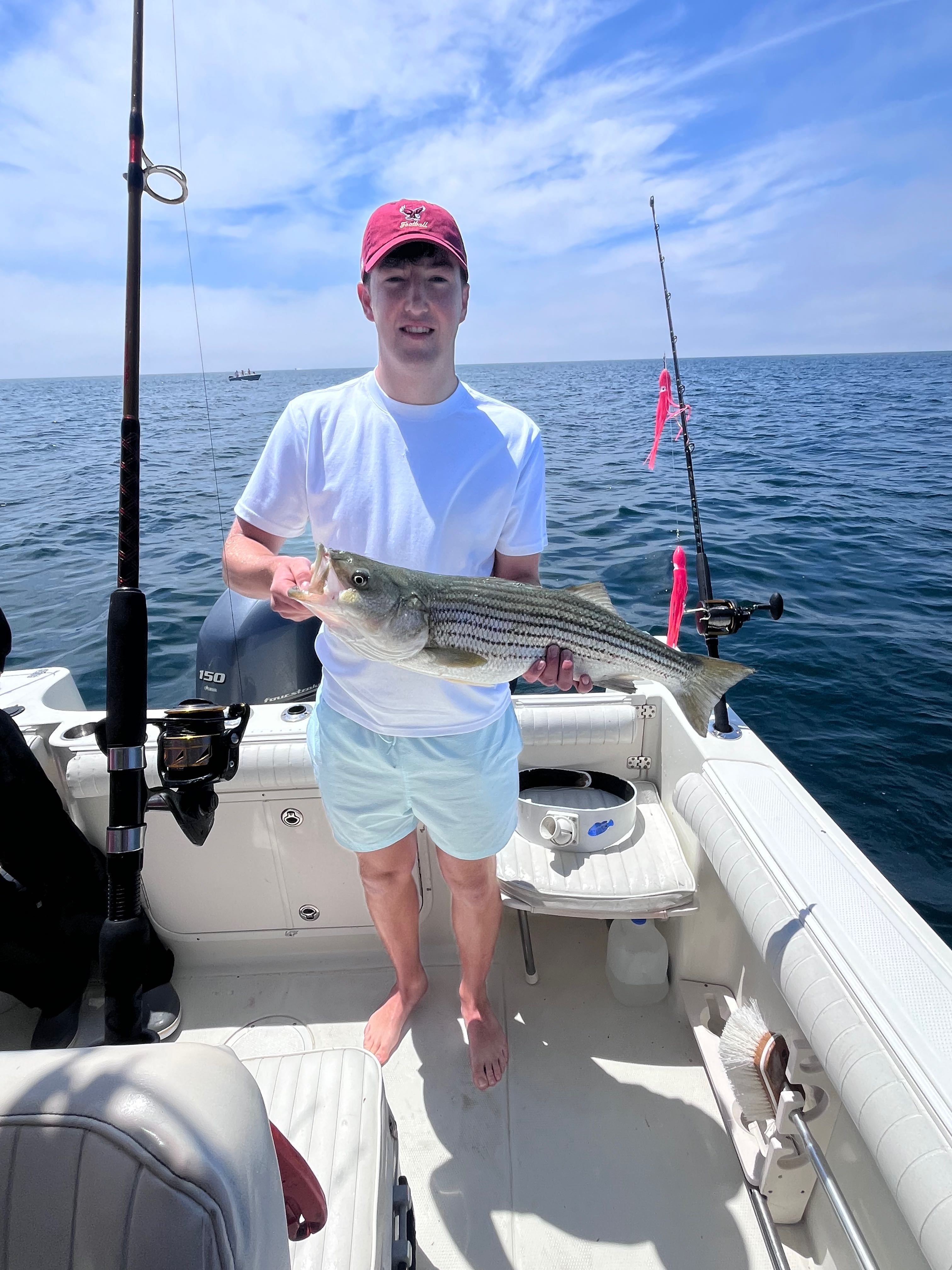 Striped bass caught while fishing in East Dennis MA on boat deck with fishing rods visible