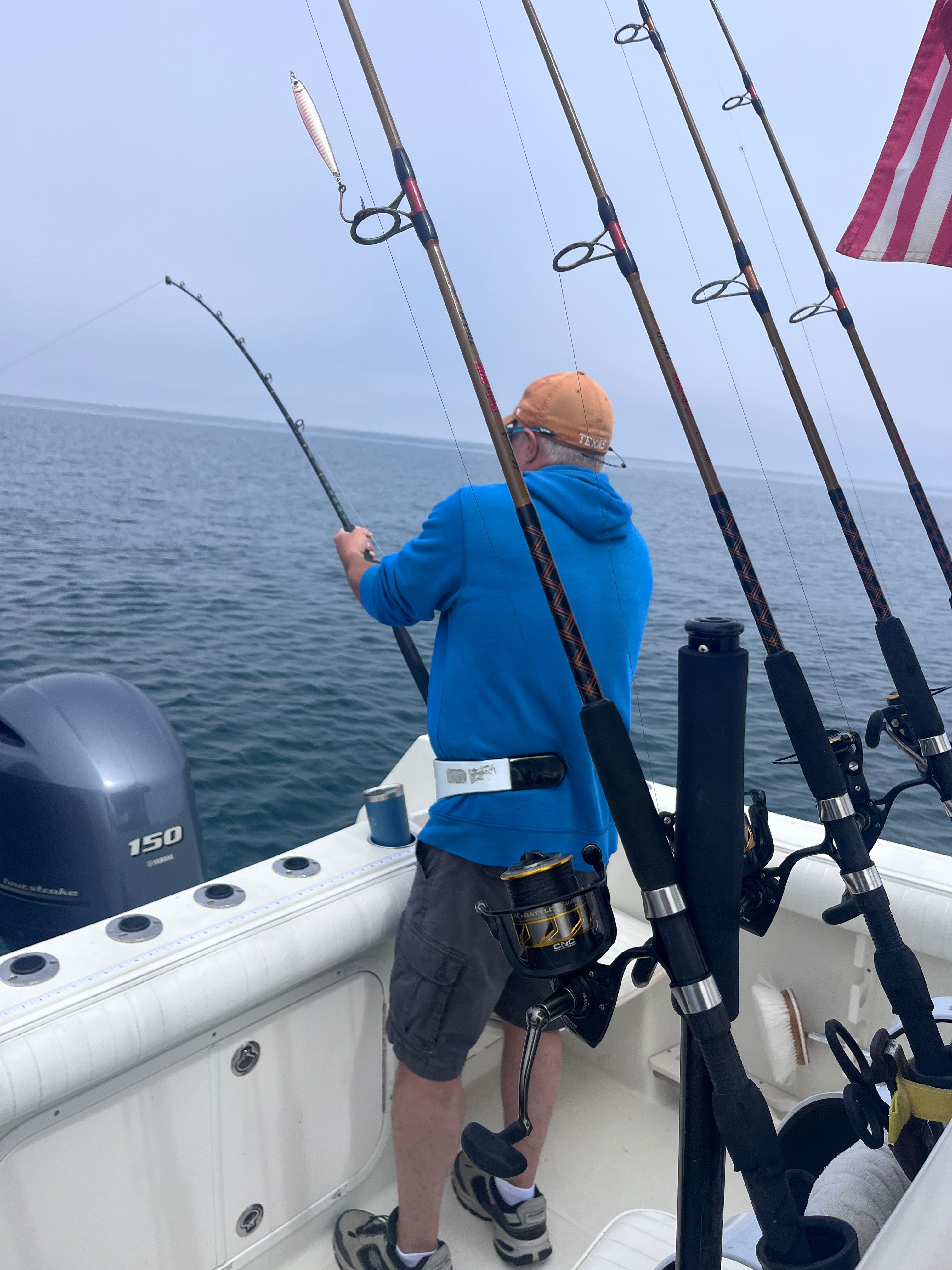Fishing rods setup on boat deck in East Dennis MA waters with outboard motor visible