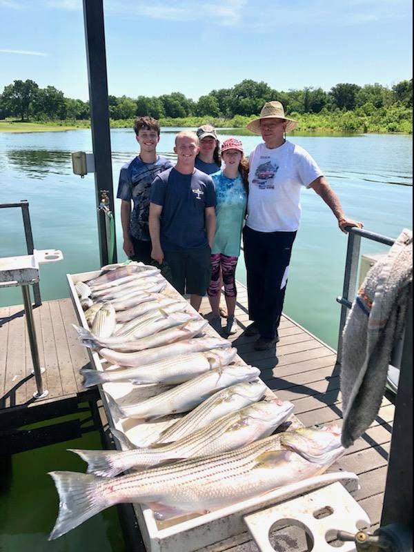 Successful striped bass fishing trip in Kingston OK with multiple fish displayed on dock