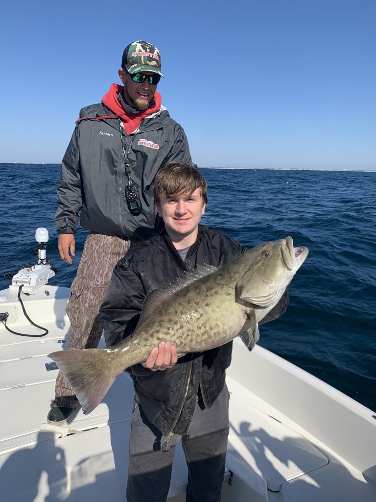 A gag grouper fish being held by two people in Pensacola