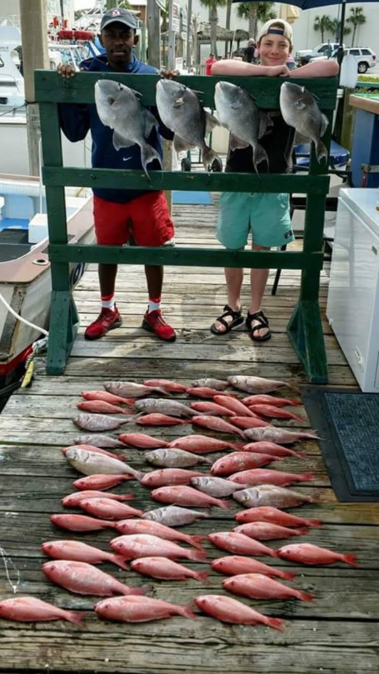 Fishing charter displaying catch of grey triggerfish and red snapper on dock in Panama City Beach FL