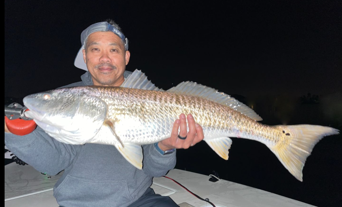 Angler holding a large redfish caught in Edgewater