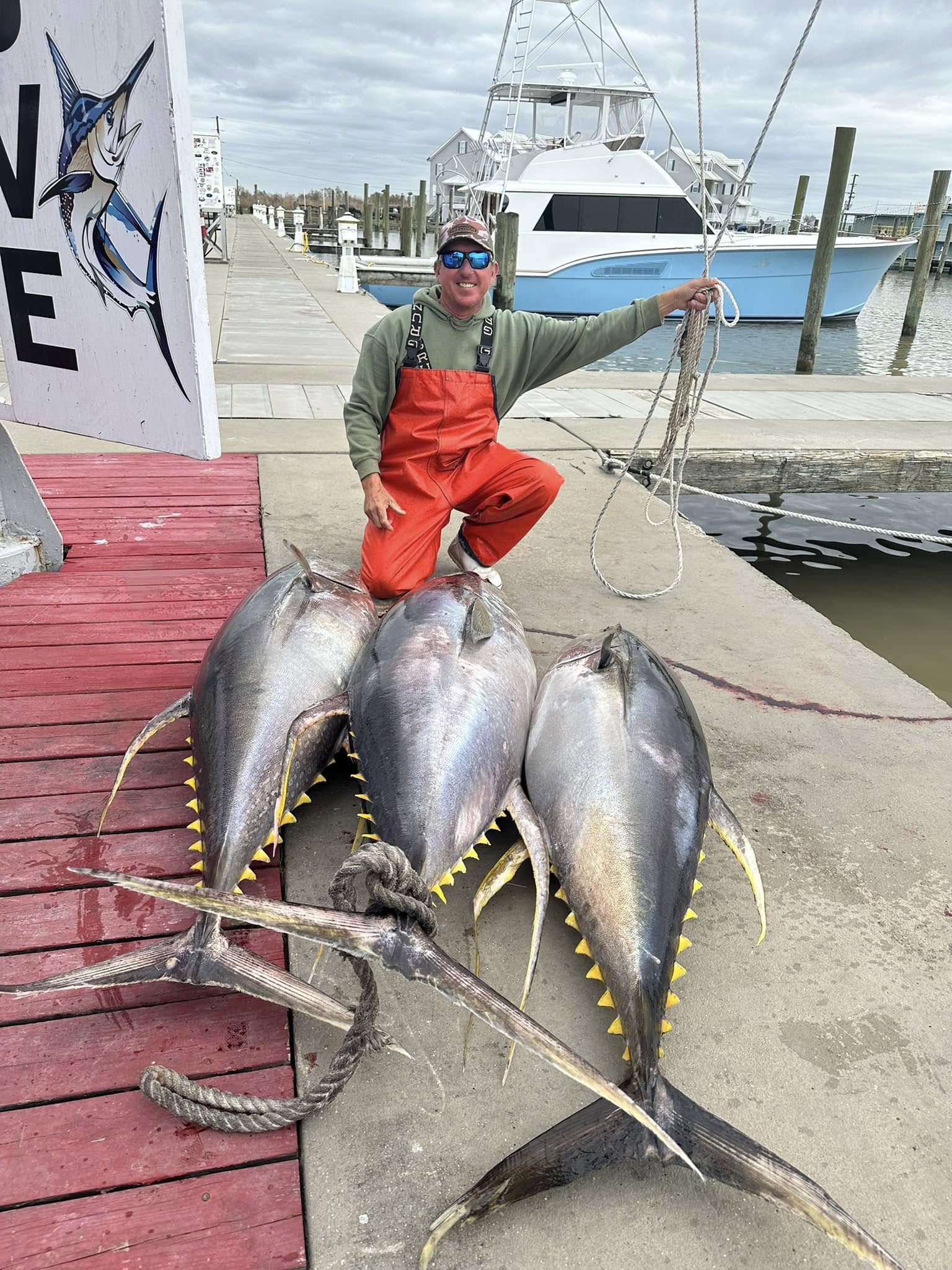 A fisherman holds 3 large tuna and mackerel fish in LA