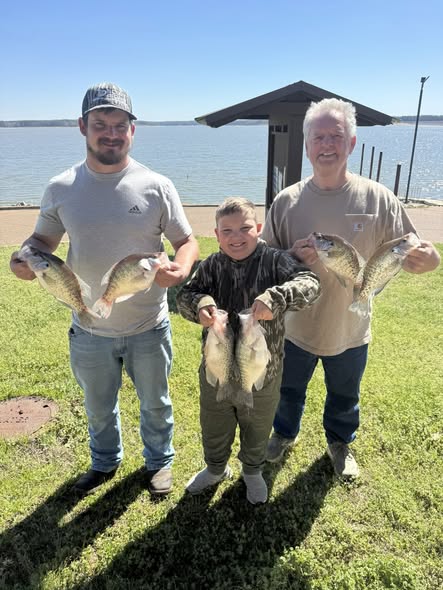 Successful fishing trip in Pope MS showing multiple caught fish displayed on grassy area near lake with dock structure