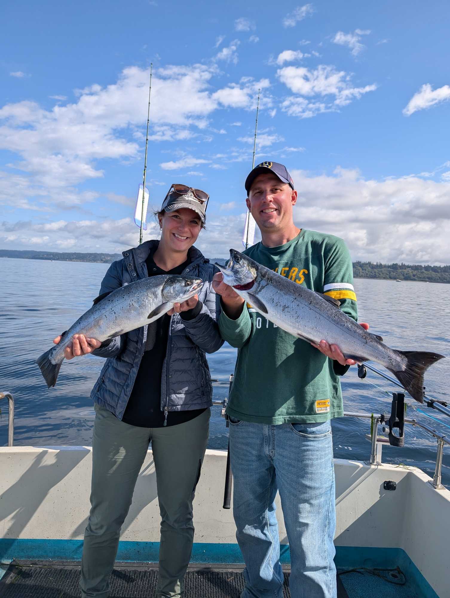 Two anglers displaying freshly caught Coho and Atlantic salmon on fishing boat in Edmonds WA