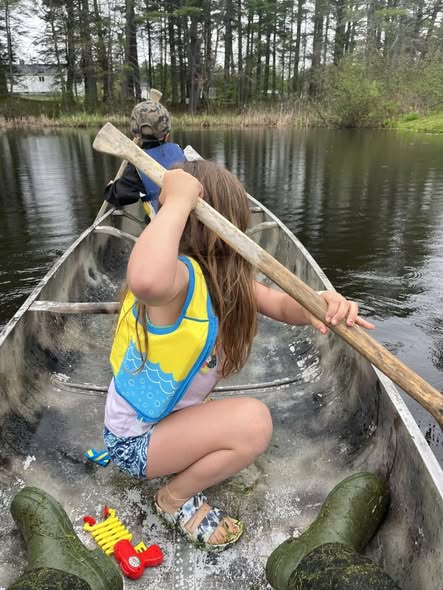 Canoe on calm water with paddle and fishing equipment in Brownville ME