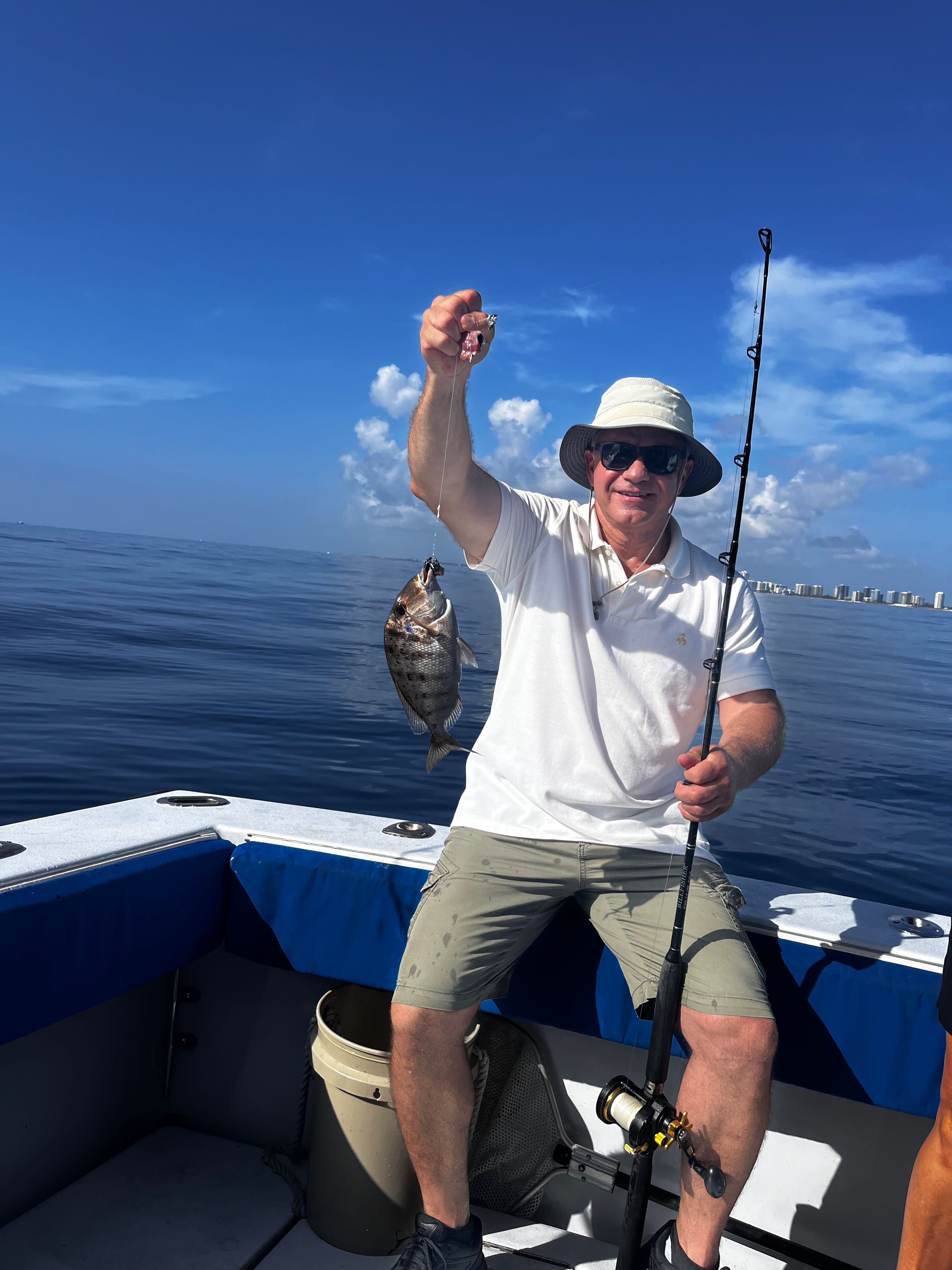 Angler holding freshly caught fish on fishing boat in Riviera Beach FL waters