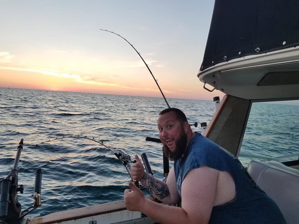 Fishing rod bent with catch on boat in Racine WI waters at sunset