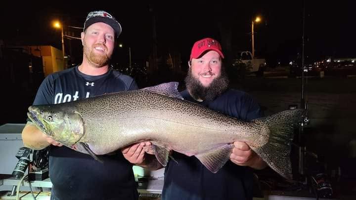 Two anglers displaying large Chinook salmon catch at night in Racine Wisconsin