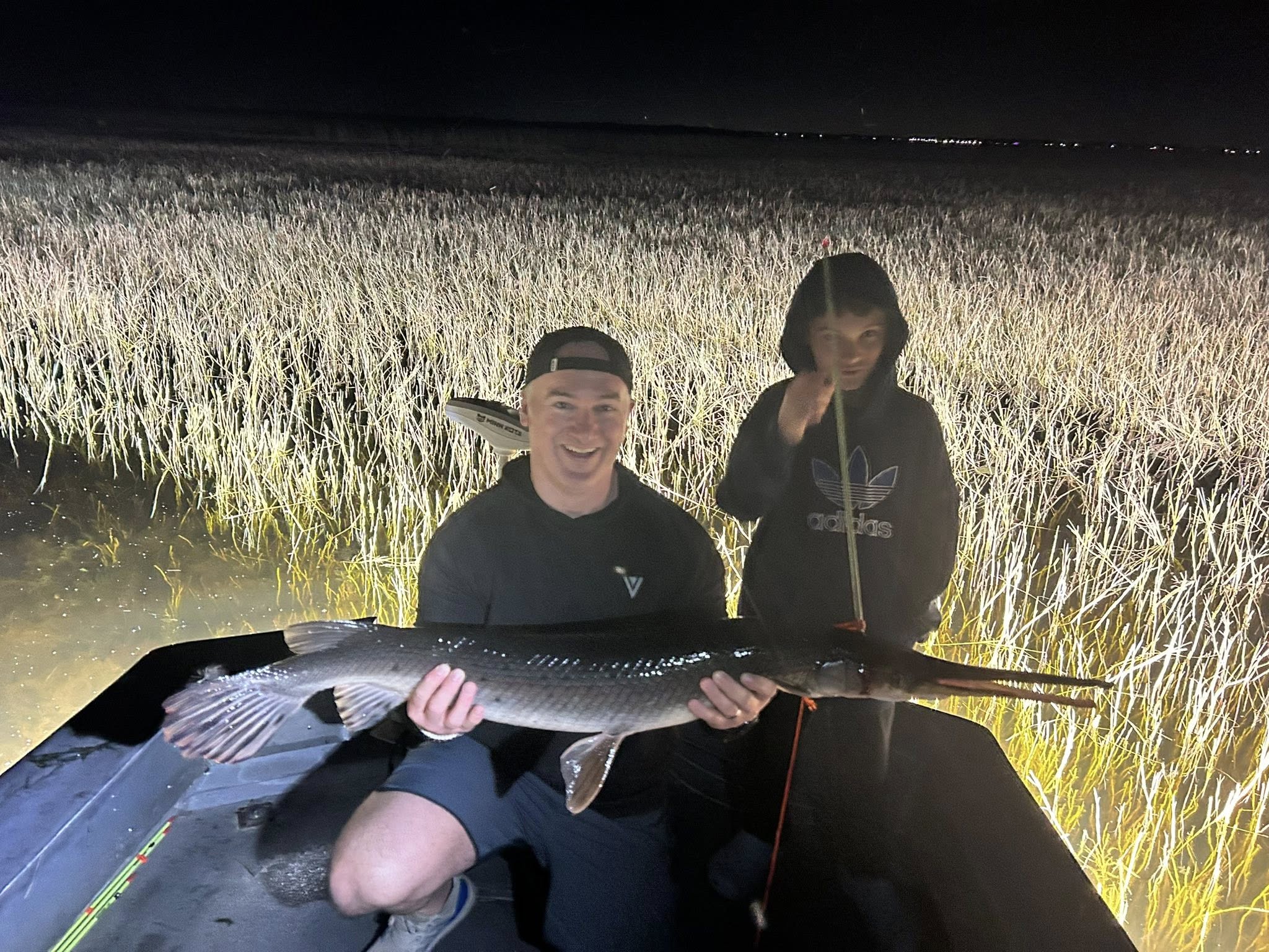Shortnose gar catch displayed at night in Saint Cloud FL with tall marsh grass in background