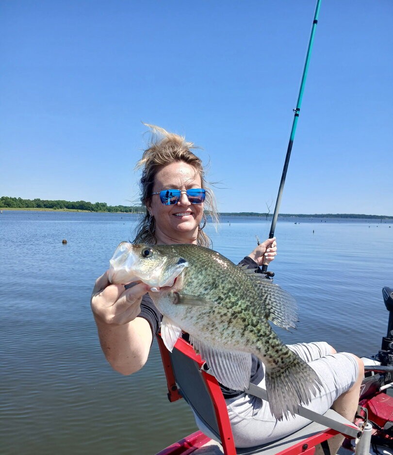 Angler holding freshly caught crappie fish on lake in Quitman Texas