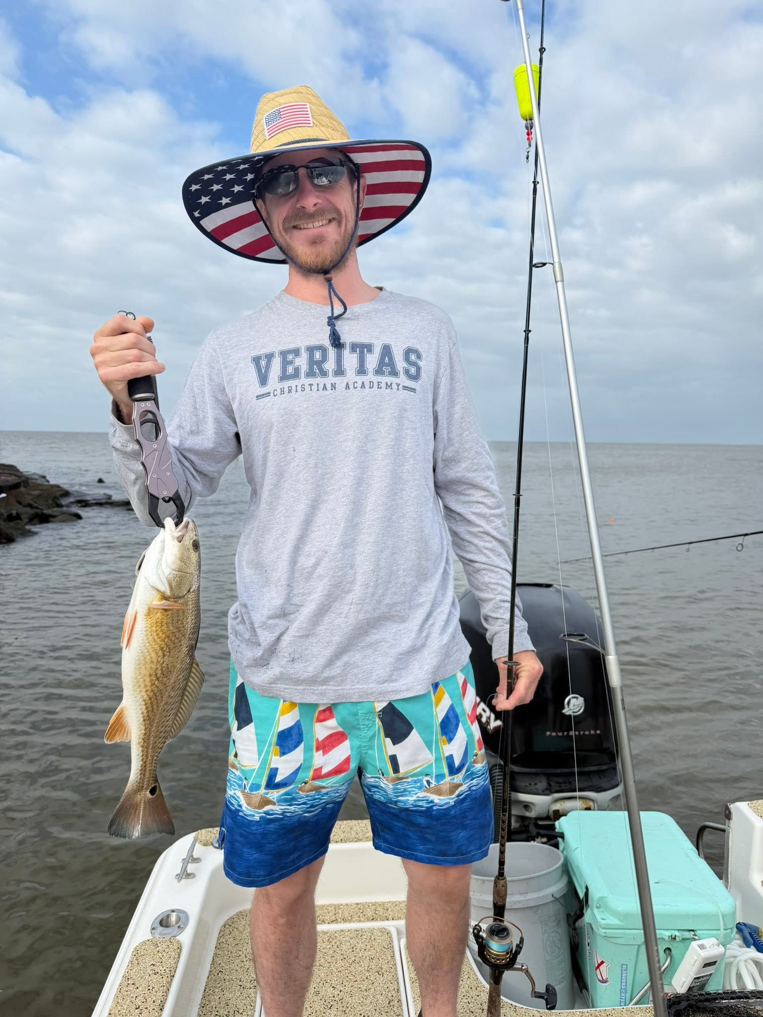 Angler holding caught redfish on fishing boat in Spanish Fort AL waters