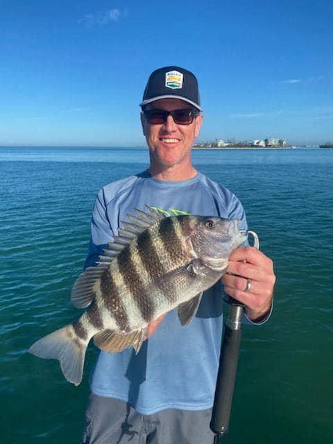 A fisherman holding a Sheepshead fish measuring 18 inches, caught in Placida.