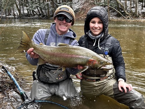 A fisherman holding a large, pink salmon in MI