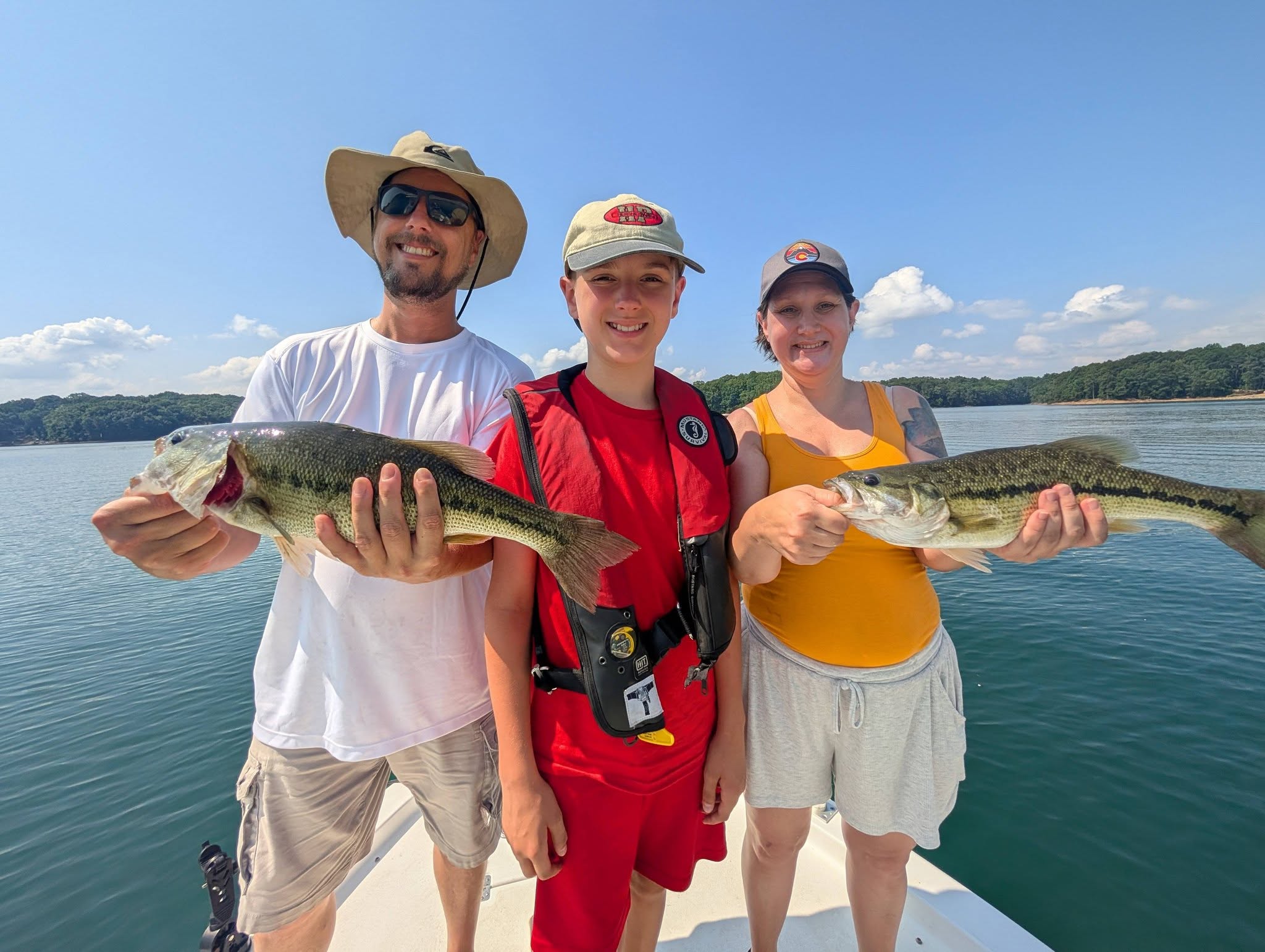 Three anglers displaying spotted bass catches on boat in Gainesville GA lake