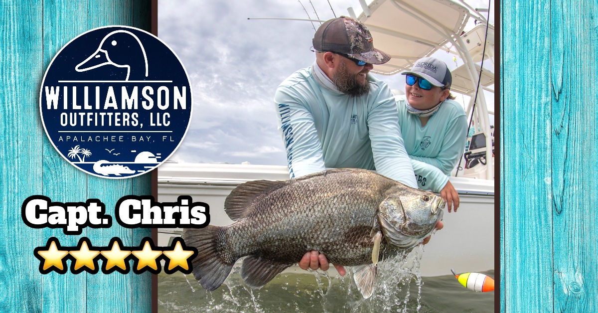 A fisherman holding a large black drum fish in FL