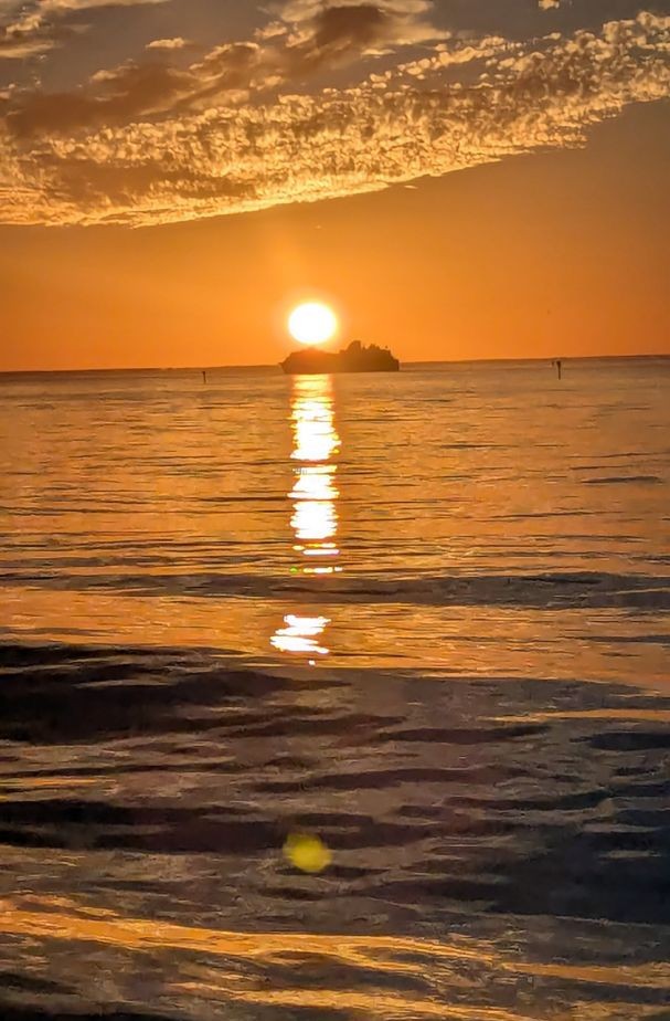 Sunset over calm water with silhouetted island in Ruskin FL fishing location