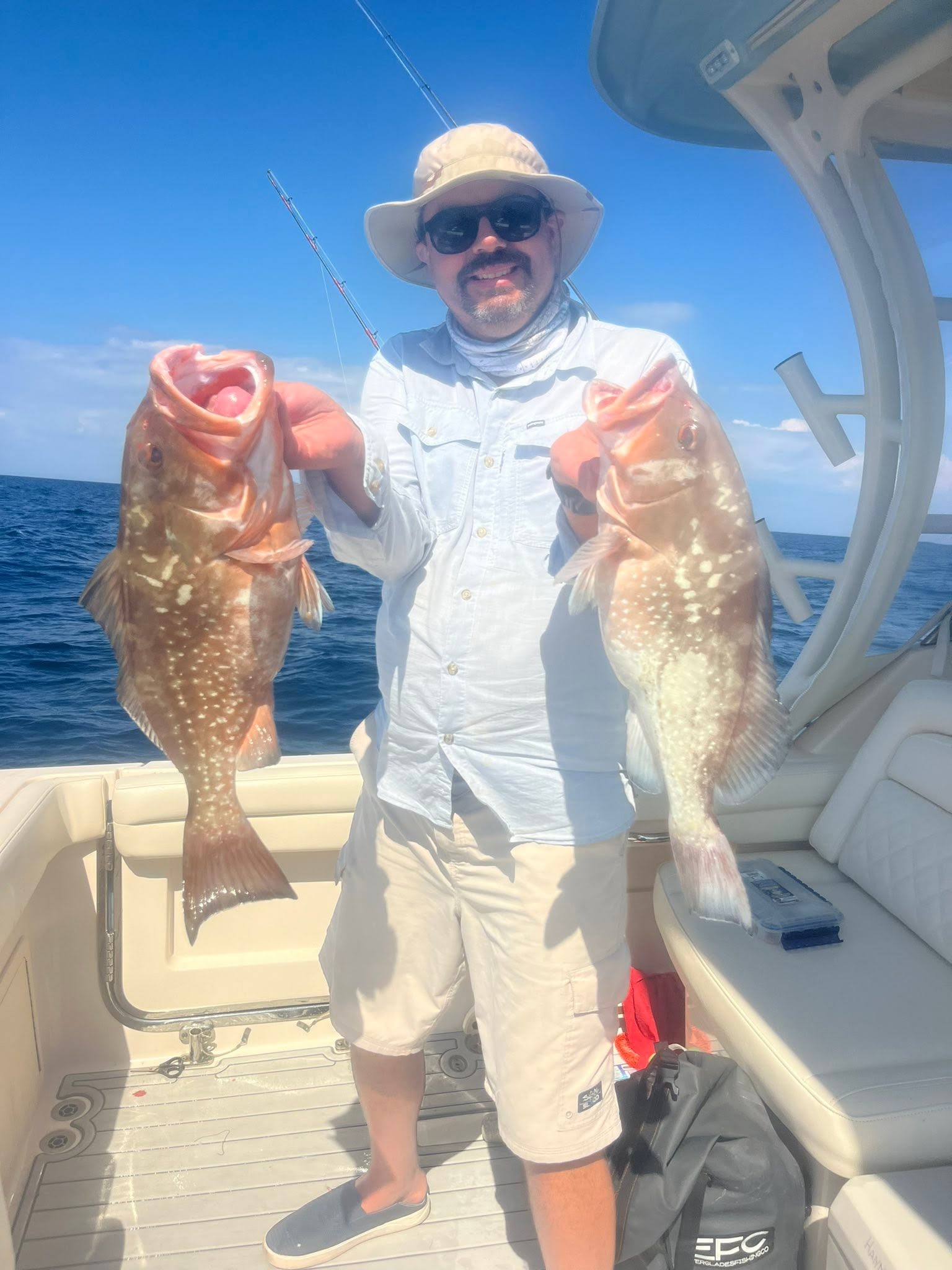 Angler holding two red grouper fish on fishing boat in Sarasota FL waters
