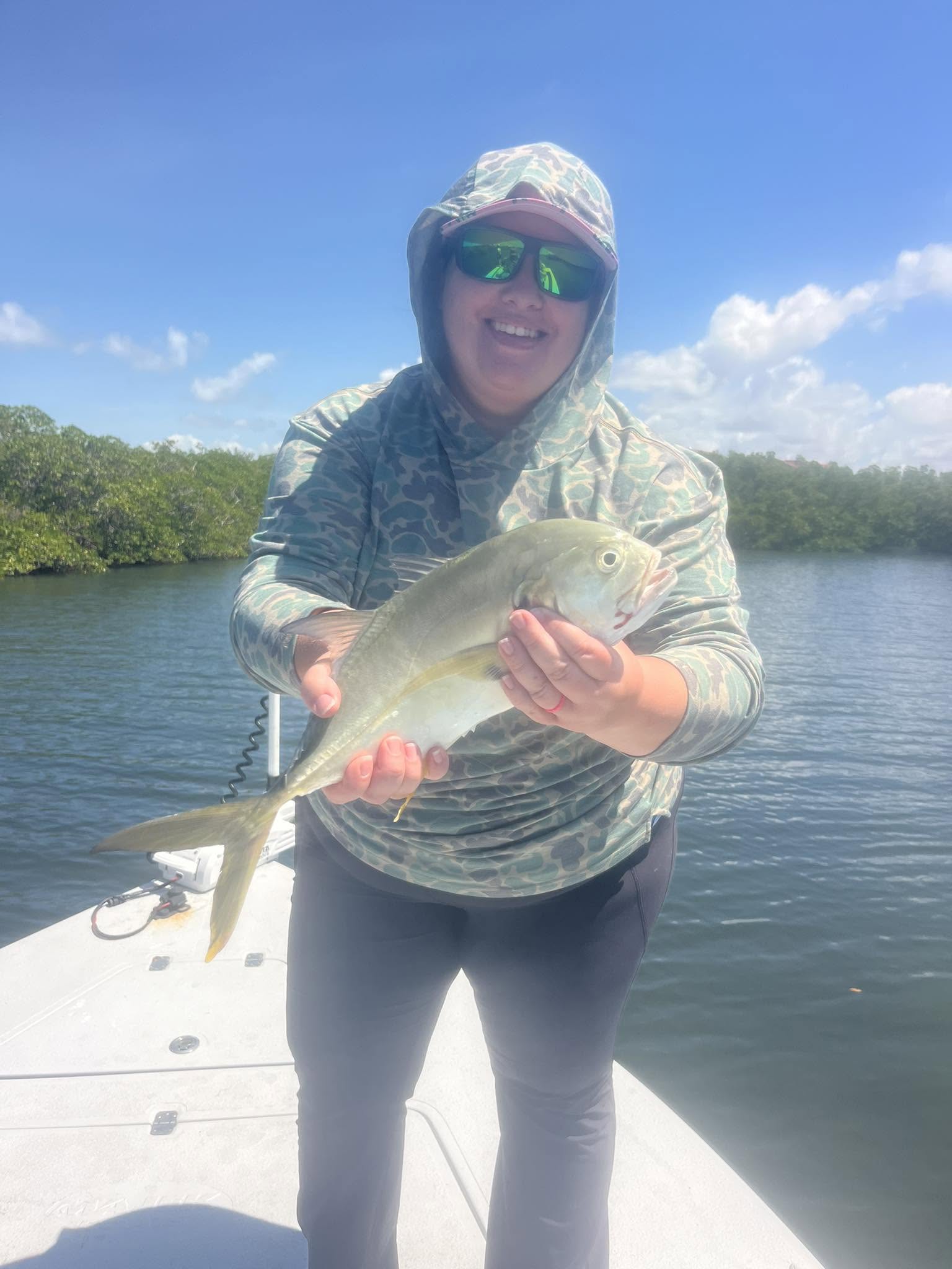 Angler holding caught fish on boat in Sarasota FL waters with mangroves in background